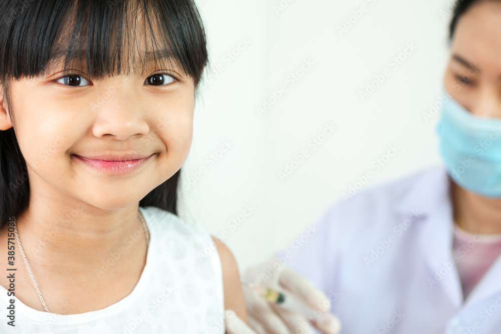 Fototapeta premium Asian child girl in a white shirt is vaccinating or taking medicine at the hospital with a smiling face on a white background