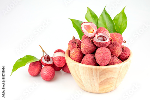 Lychee Hong Hui in a wooden bowl with branches and green leaves on a white background