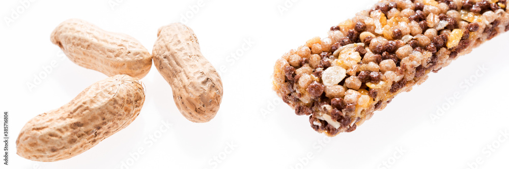 Healthy granola bar (muesli or cereal bar) and peanuts isolated on white. Panoramic image Healthy granola bar (muesli or cereal bar) and peanuts isolated on white. Panoramic image