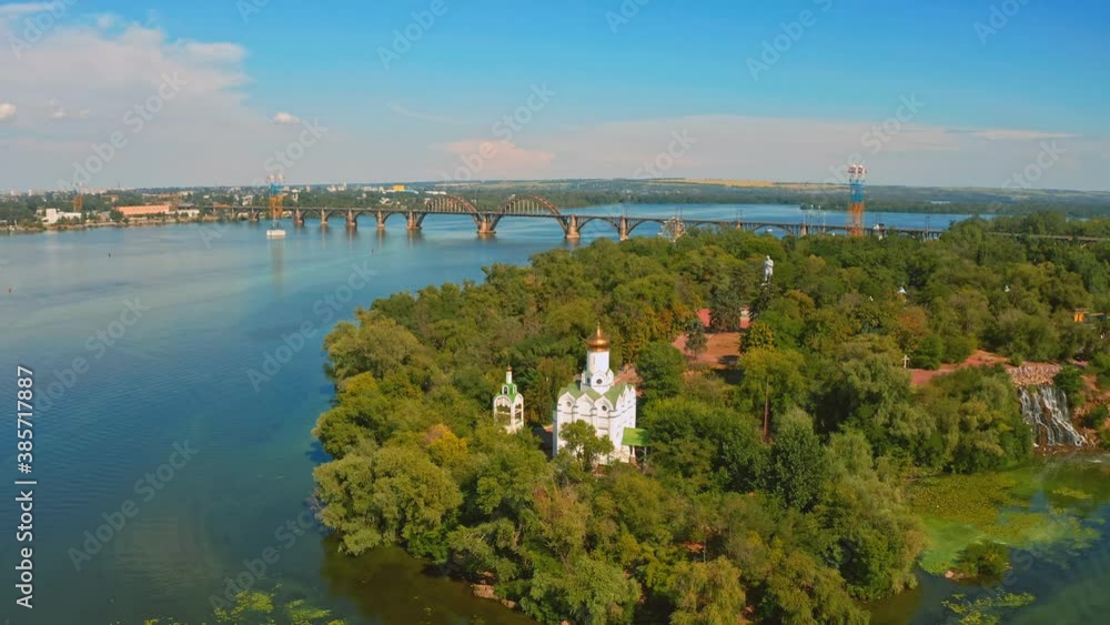 Aerial view over beautiful white church on island surrounding by river - while sunset. Drone flying above old church Aerial view over beautiful white church on island surrounding by river - while sunset. Drone flying above old church