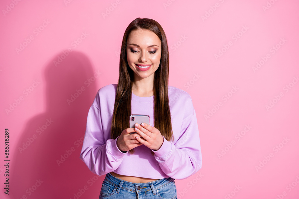 Photo of positive girl use cellphone read social network news post comment share repost wear violet denim jeans isolated over pastel color background Photo of positive girl use cellphone read social network news post comment share repost wear violet denim jeans isolated over pastel color background