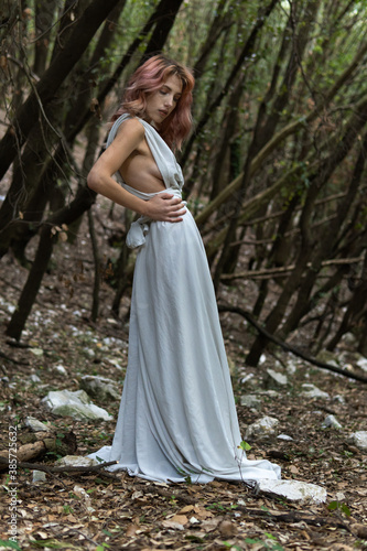 A woman in a white dress in the middle of the forest