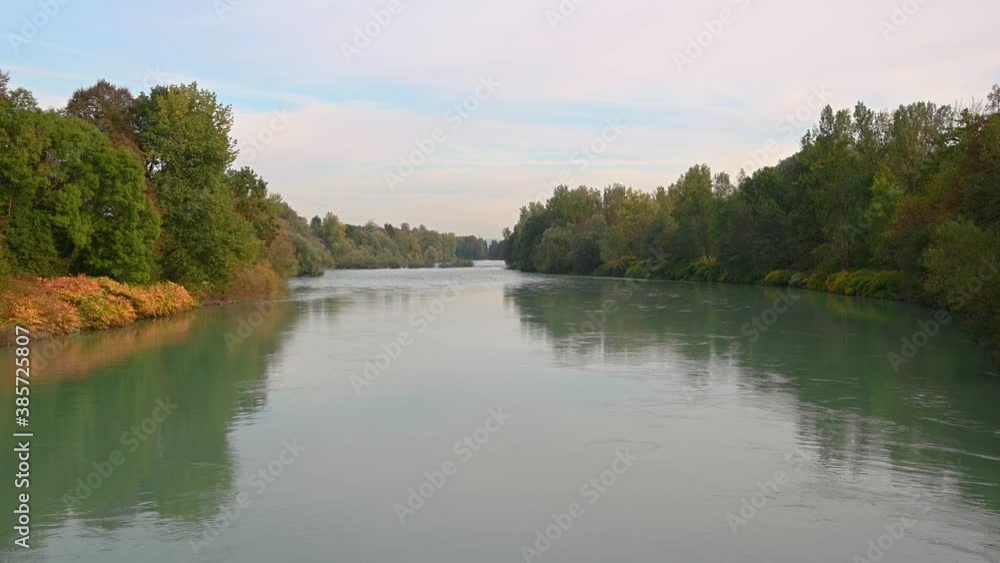 Elevated view of green calm Sava river flows downstream. Wide green river in Slovenia surrounded with colorful forest in autumn season. Static shot, real time, 4K Elevated view of green calm Sava river flows downstream. Wide green river in Slovenia surrounded with colorful forest in autumn season. Static shot, real time, 4K