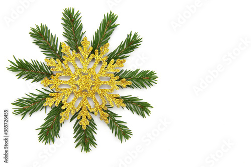 Green branches of a Christmas tree  a Golden snowflake on top on a white isolated background. Traditional Christmas decoration  decor. The view from the top. Flatly. Copy space.