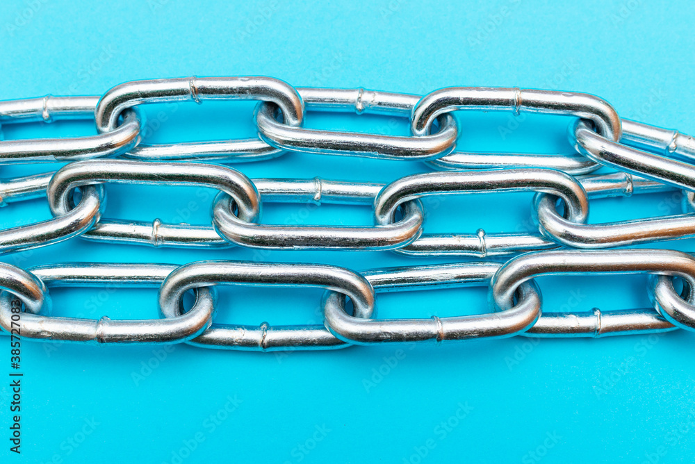 Fototapeta premium Top view Close-up metal chain lies on the blue background .Studio shot.