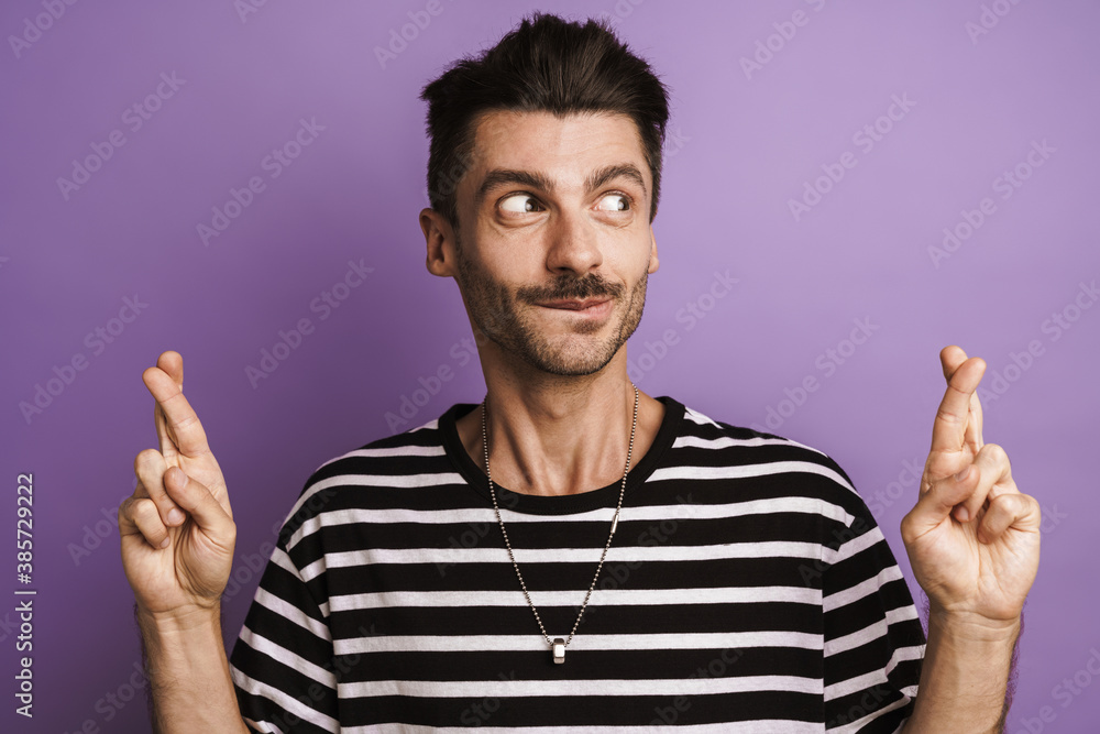 Photo of pleased handsome man posing with fingers crossed Photo of pleased handsome man posing with fingers crossed