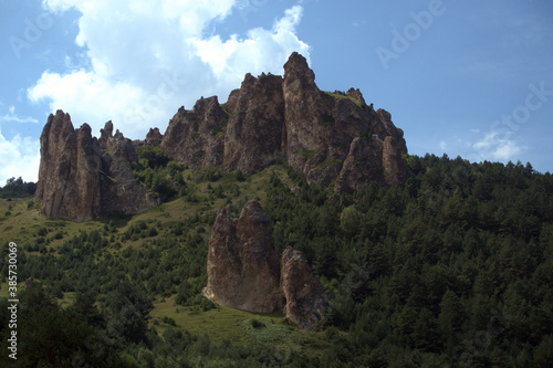 High steep rock. Landscape with a sheer cliff surrounded by forest. Caucasus, Russia.