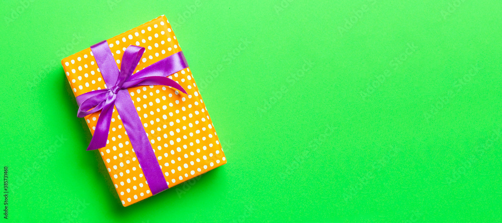 Top view Christmas present box with purple bow on green background with copy space