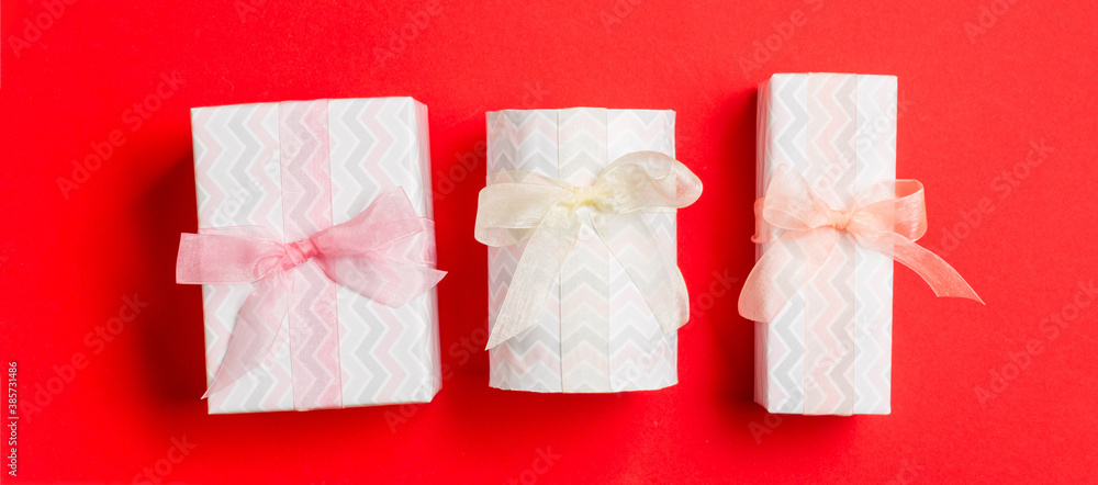 wrapped Christmas or other holiday handmade present in paper with Colored ribbon on red background. Present box, decoration of gift on colored table, top view wrapped Christmas or other holiday handmade present in paper with Colored ribbon on red background. Present box, decoration of gift on colored table, top view
