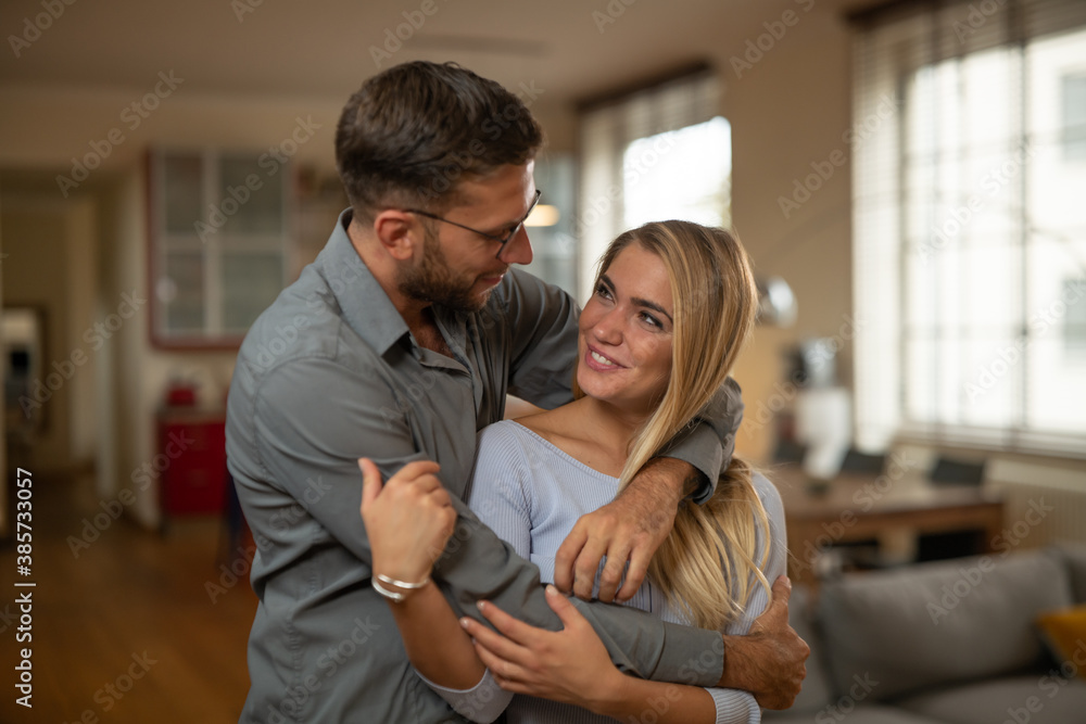 Authentic shot of young happy smiling married couple is enjoying time together is hugging as sign of timeless love in a kitchen at home. Authentic shot of young happy smiling married couple is enjoying time together is hugging as sign of timeless love in a kitchen at home.