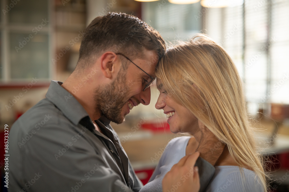Authentic shot of young happy smiling married couple is enjoying time together is hugging as sign of timeless love in a kitchen at home. Authentic shot of young happy smiling married couple is enjoying time together is hugging as sign of timeless love in a kitchen at home.