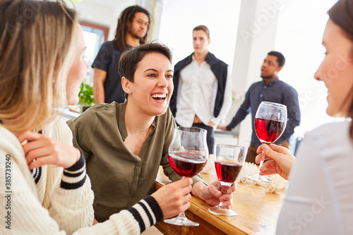 Group of women as friends at a party talking over a glass of red wine