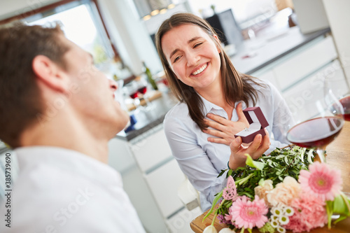 Young woman with bouquet and wedding ring on marriage proposal at home