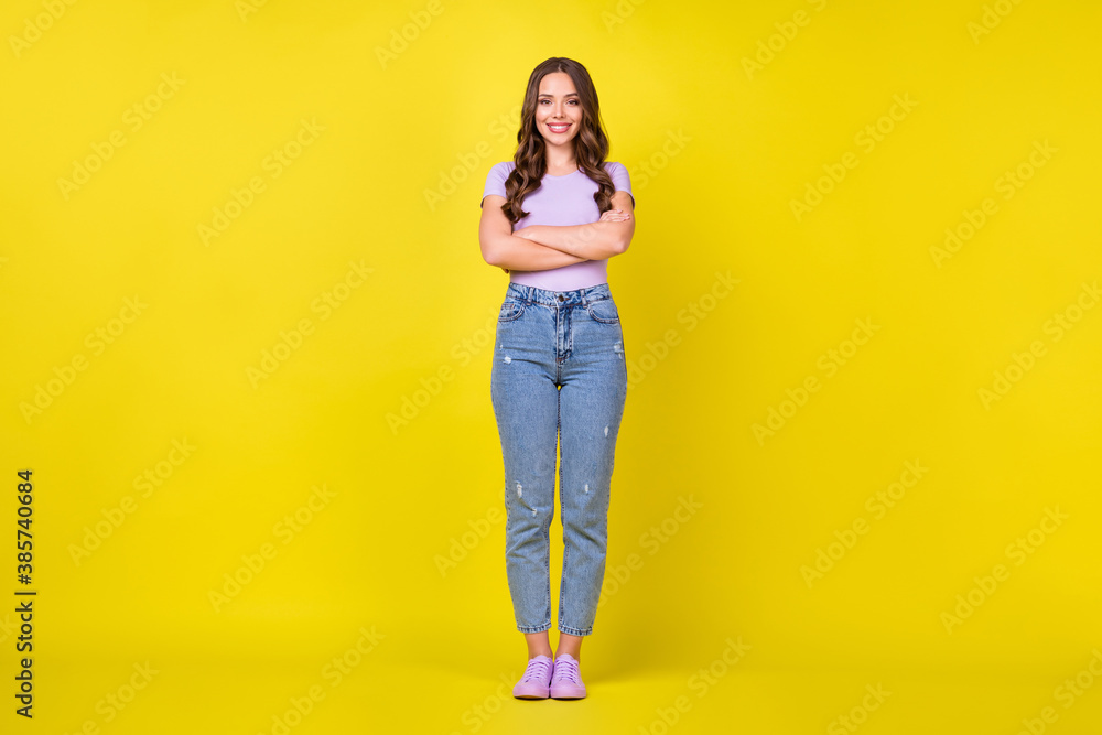 Full length body size view of attractive content cheerful wavy-haired girl folded arms isolated over bright yellow color background Full length body size view of attractive content cheerful wavy-haired girl folded arms isolated over bright yellow color background