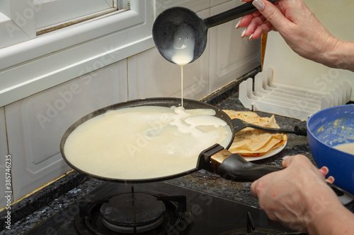 The pancake mix is ​​poured from the ladle into the skillet making a delicious breakfast for the whole family.