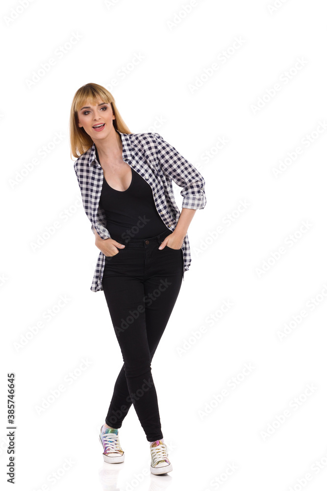 Young Woman Is Standing With Legs Crossed, Looking Away And Talking. Young Woman Is Standing With Legs Crossed, Looking Away And Talking.