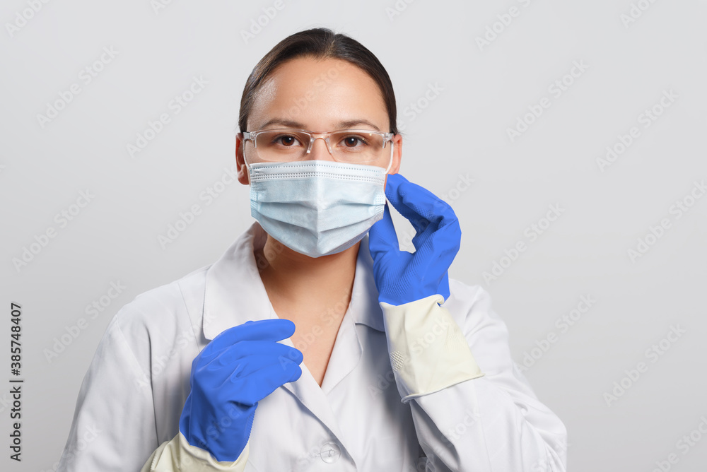 Young female doctor putting on a protective mask on her face. Young female doctor putting on a protective mask on her face.
