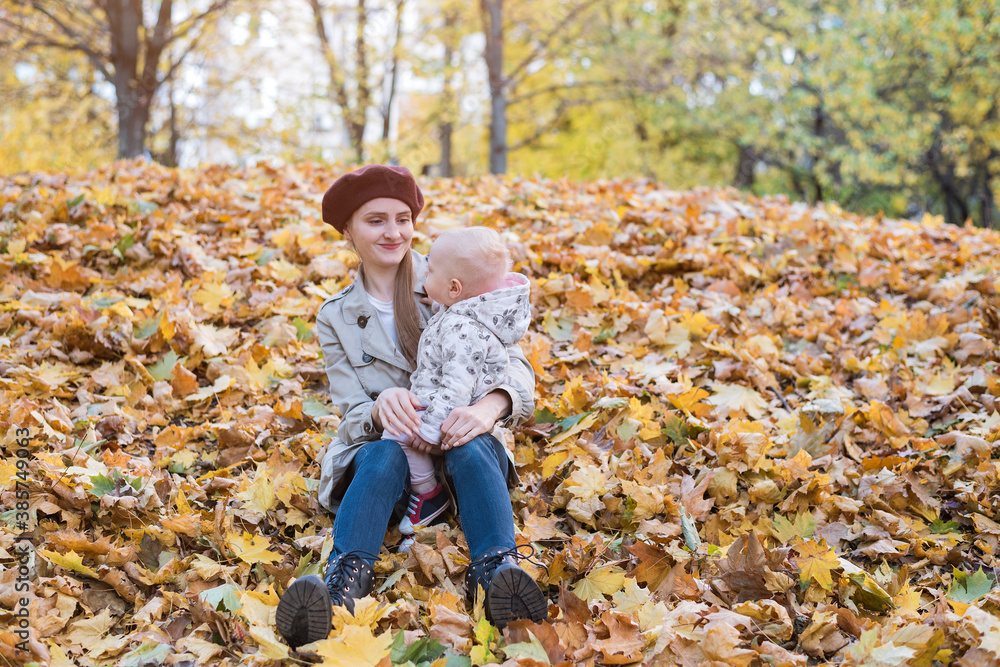 Young mother and small child sitting on yellow autumn leaves in Park. Young mother and small child sitting on yellow autumn leaves in Park.