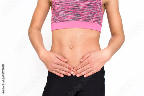Young spotr girl suffering from stomach ache isolated on white background. Female person in sportswear with pain in stomach. 