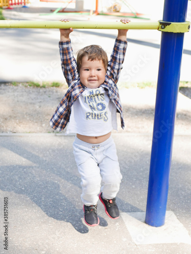 Toddler boy learning to do pull ups on the playground.