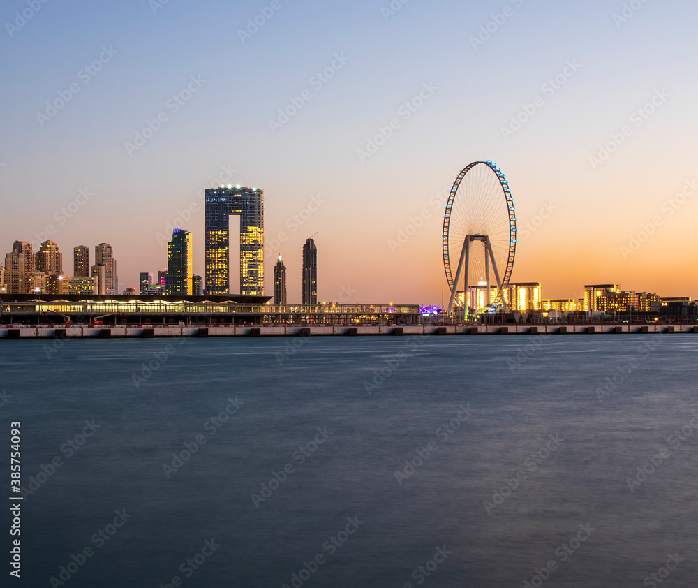 Obraz premium View of A Jumeirah Beach Residence and Blue watersafter sunset. Shot made from Palm Jumeirah, man made island. Tallest ferris wheel, Ain Dubai can also be seen in the scene Dubai, UAE.