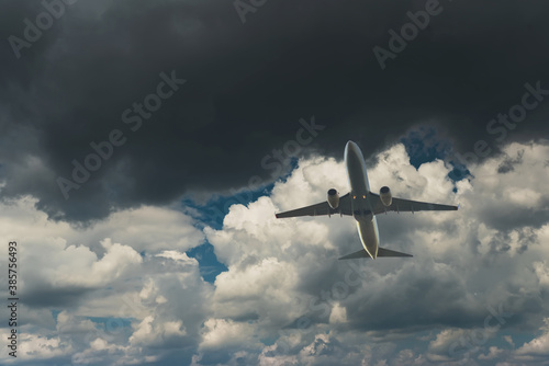 Commercial airplane flying through clouds in dramatic sky. Travel concept