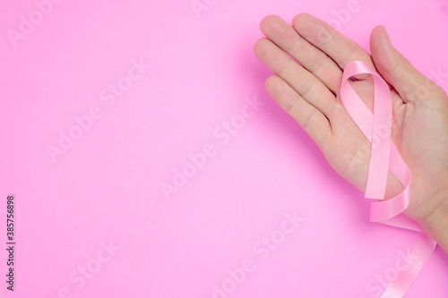 breast cancer awareness ribbon on hand palm and on pink background