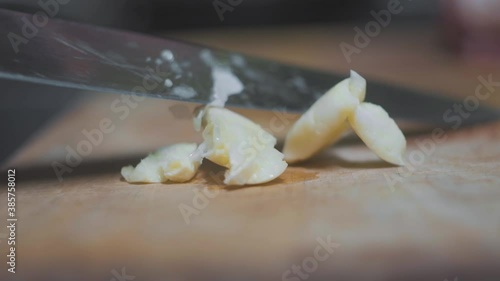 hands crush garlic on a wooden board with a knife close-up