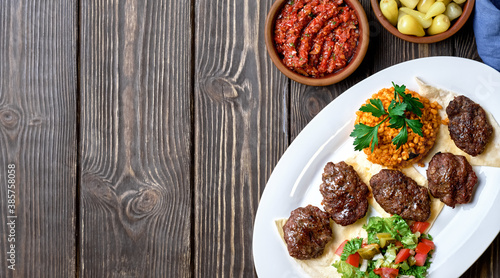 Kofte (köfte) - Turkish cutlets (meat balls) made from lamb and beef meat and spices, cooked over charcoal. Served on a platter with salad and bulgur. Top view with copy space