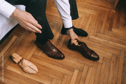 Close up of the feet of the groom or business man who is putting on new stylish shoes.