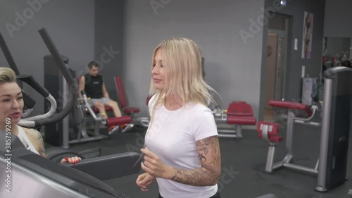Blonde in the gym running on the treadmill during a workout. Slow motion video.