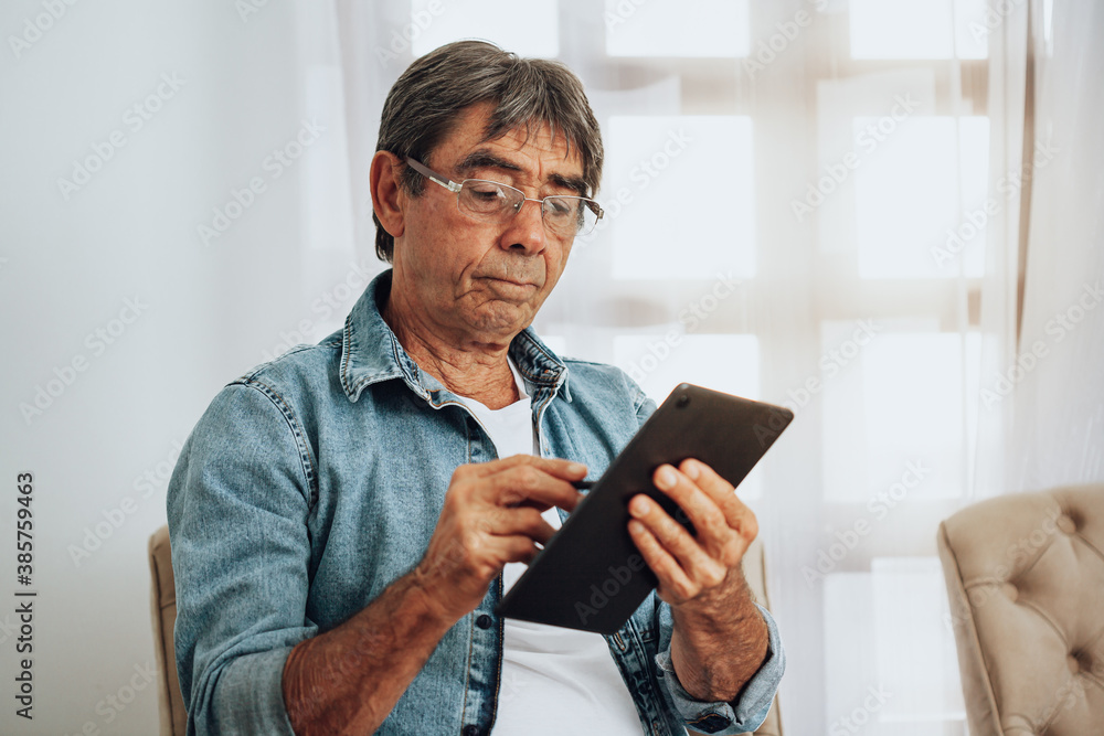 Senior man working on digital tablet at home Senior man working on digital tablet at home