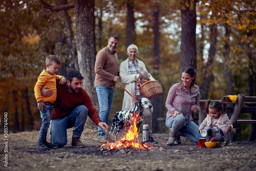 A happy family and their dog enjoying a campfire in the forest