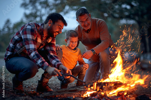 Father, son and grandson lit up a campfire in the forest
