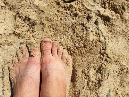 Feet on the sand, top view, soft focus