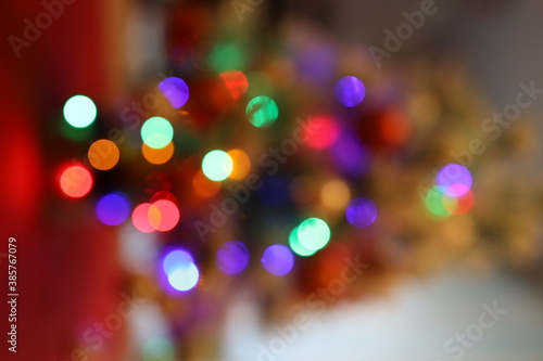 Die bunten und verschwommenen Lichter eines kleinen und weißen Weihnachtsbaumes stehend auf einem roten Tuch.