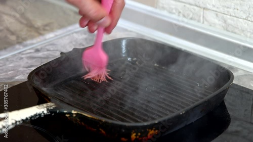 Close up view of male cook grease grill pan with vegetable oil and lay out onion rings. Man cooking dinner on kitchen, simple vegan dietary meals, home-cooking tips, healthy recipe, lifestyle concept