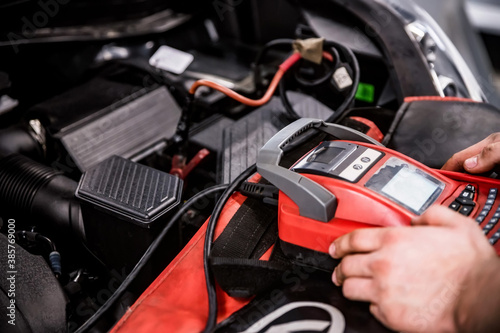 Hands of car mechanic checks auto battery charge