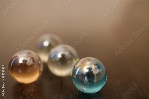 Große und glänzende Glaskugeln in verschiedener Anzahl auf einem braunen Holztisch. Sie repräsentieren die vier oder fünf Elemente.