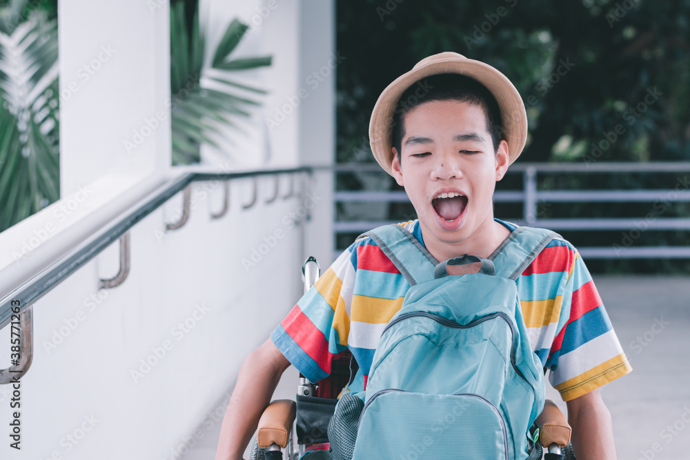 Disabled child on wheelchair is smiling,Wear a sun hat,bright colored T shirt,blue backpack,Prepare for outdoor picnic with family,Lifestyle of special child,Lifestyle of happy disability kid concept. Disabled child on wheelchair is smiling,Wear a sun hat,bright colored T shirt,blue backpack,Prepare for outdoor picnic with family,Lifestyle of special child,Lifestyle of happy disability kid concept.