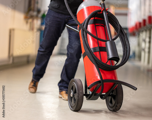 Man moves a wheeled fire-extinguisher. photo