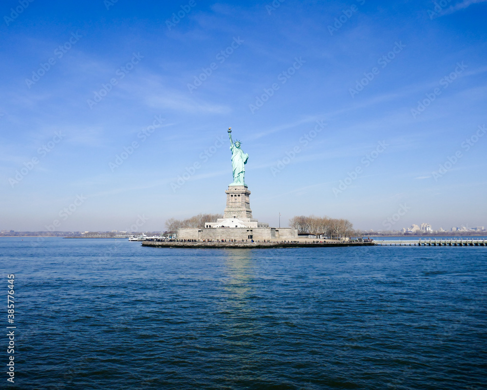 Statue of Liberty in NY Harbor on bright sunny day with blue sky Statue of Liberty in NY Harbor on bright sunny day with blue sky