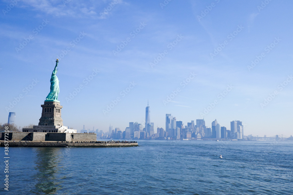Statue of Liberty in NY Harbor on bright sunny day with blue sky and Manhattan in the distance Statue of Liberty in NY Harbor on bright sunny day with blue sky and Manhattan in the distance
