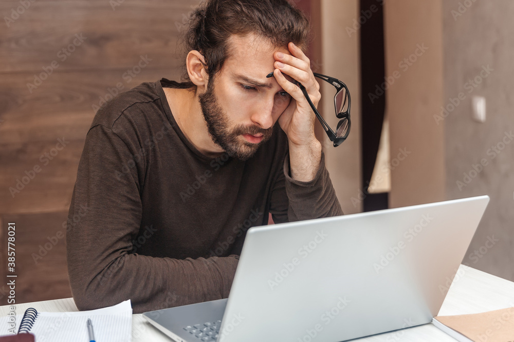 Tired man looking at laptop while working Tired man looking at laptop while working