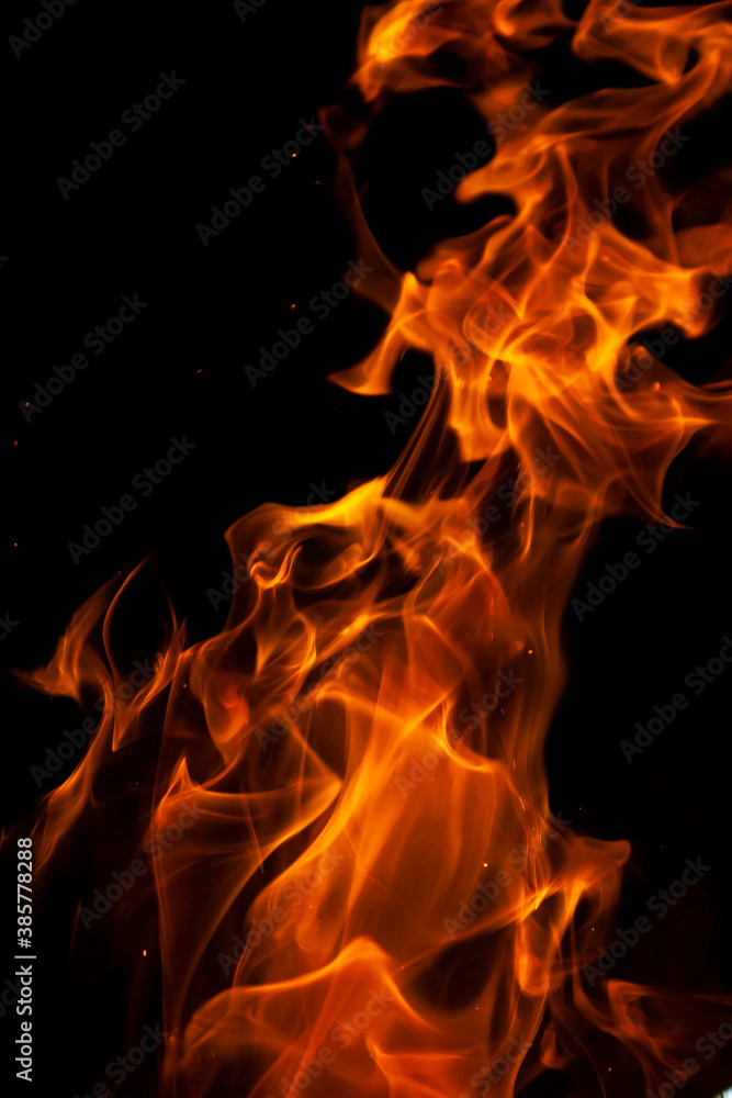 Close-up picture of a burning brightly orange hot flame with on the black background 