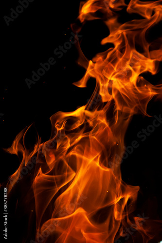 Close-up picture of a burning brightly orange hot flame with on the black background 
