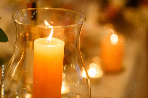 Burning candle in a tall transparent glass
