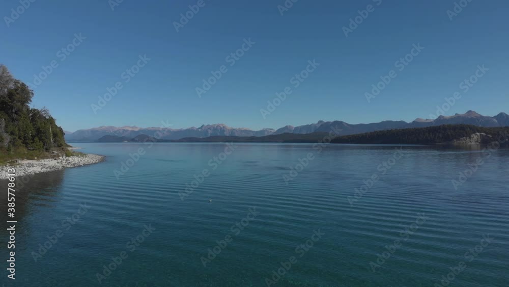 Drone view over a lake with turquoise waters, seagull floating. Clear sky in summer. Andres mountains in the background. Drone moving forward. Drone view over a lake with turquoise waters, seagull floating. Clear sky in summer. Andres mountains in the background. Drone moving forward.