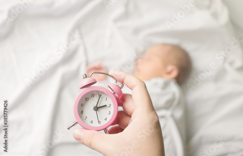 Sleeping newborn baby in a wrap on white blanket. Beautiful portrait of little child girl, one week old.