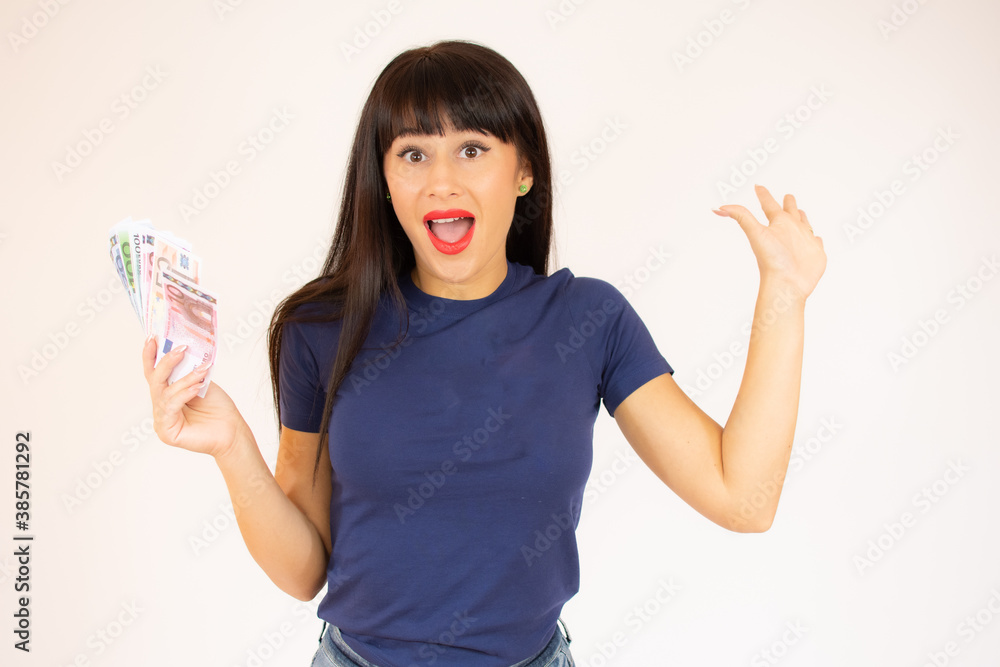 Obraz premium Portrait of a smiling young girl showing bunch of money banknotes isolated over white background